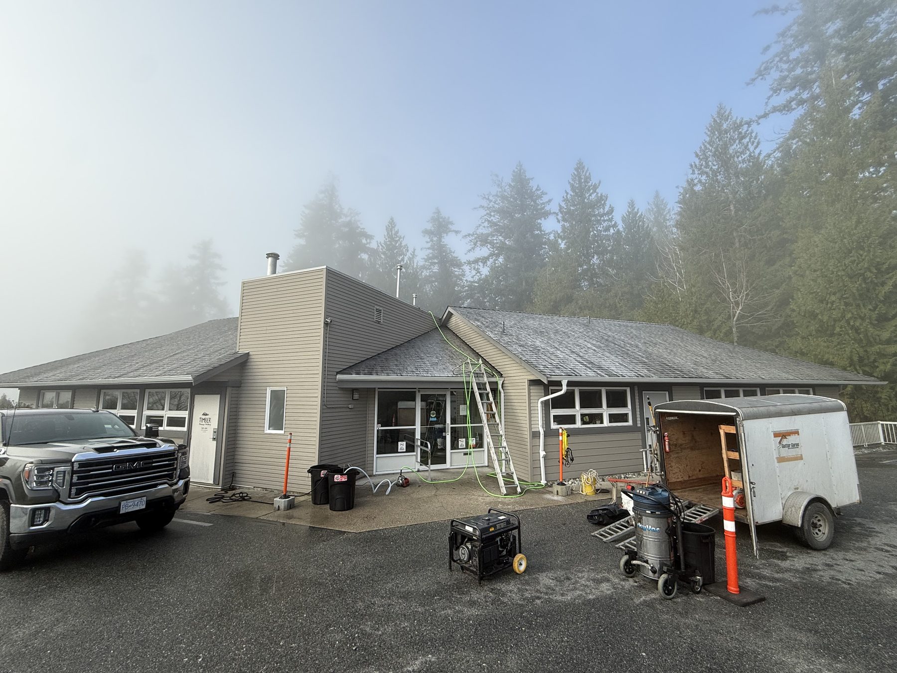 Commercial building job — truck, trailer, ladder, and equipment on site